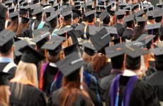 College graduates facing away from the camera standing for graduation