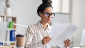 Woman with glasses reviews papers.