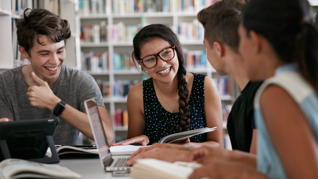 A group of four students chat in a library.