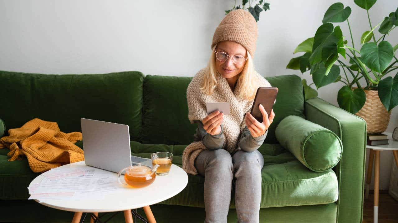 Woman paying bills while sitting on sofa