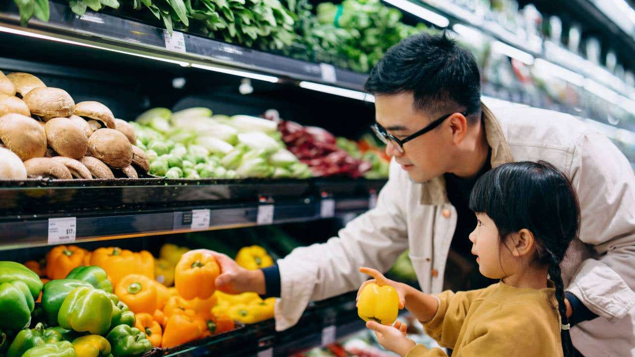 Asian father and daughter shopping at grocery story