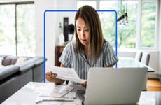 An Asian woman looks at paperwork.