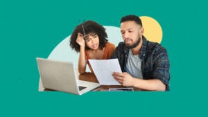 Couple looking concerned as they review financial documents while in front of an open laptop computer.