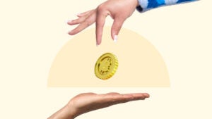 A hand drops a bitcoin into an outstretched hand below.