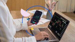 Close-up of someone's hands. They're doing work on a laptop and cellphone simultaneously