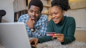 Young black couple using credit card and laptop