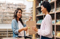 Happy young shop owner receiving a credit card from a customer