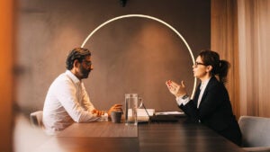 Two people having a discussion at a conference room table.