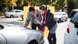 Drivers examining damage to car after an accident