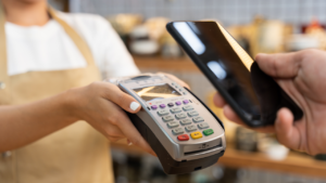 Customer making a contactless payment on a smartphone in the pottery shop