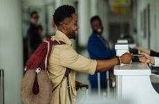 Black man handing passport at airport check in counter.