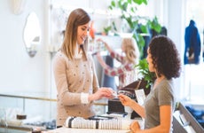 Woman checks out at store counter by paying with her credit card.