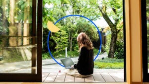 A woman sitting on a porch looking at a laptop