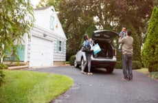 Family standing near car on driveway outside house
