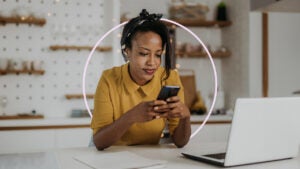 Woman sitting at desk while looking at cell phone