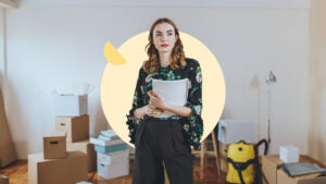 woman with moving boxes behind her and paperwork in hand