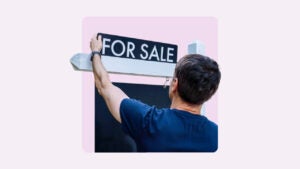 A person putting up a "For sale" sign