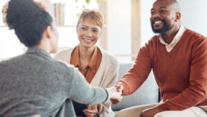 Black couple, financial advisor and handshake on home sofa