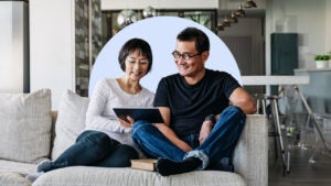 Couple sitting on couch looking at tablet