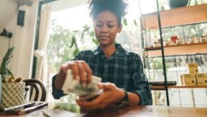 A young woman counts dollar bills