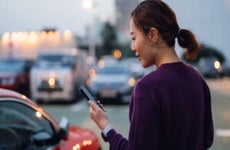 Person on smartphone standing near car