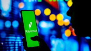 Woman holds a smartphone with the Robinhood Markets logo displayed