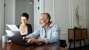 Couple discussing business paper sitting in front of laptop