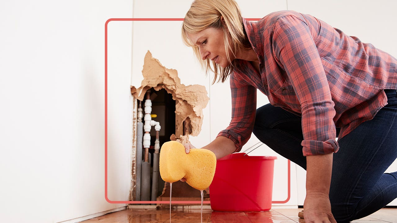 Woman cleaning up leak coming from pipes inside a wall in her home