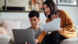 Young couple discussing over financial bills while using laptop on sofa