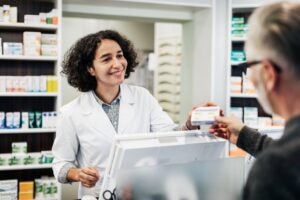 female pharmacist wearing white lab coat interacting with customer