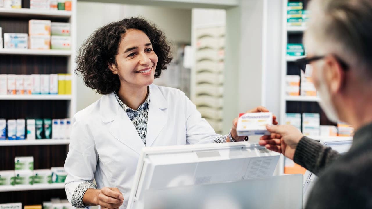 female pharmacist wearing white lab coat interacting with customer