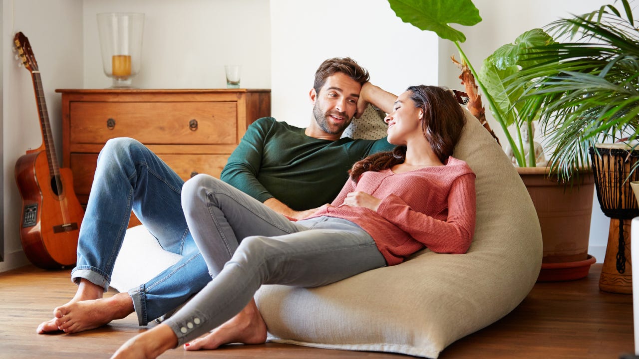 Shot of a smiling young couple talking together while relaxing on a beanbag sofa