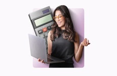 A woman with glasses holds a laptop and there's a calculator behind her.