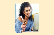 design image of a woman holding a credit card in her hand and smiling at her laptop screen