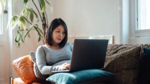 Young pregnant businesswoman at home office, working with laptop on sofa