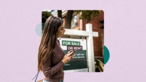 Woman on cell phone standing in front of a home for sale sign