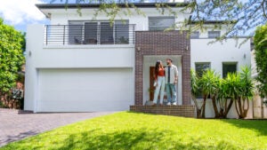 Couple standing proudly in front of their new home