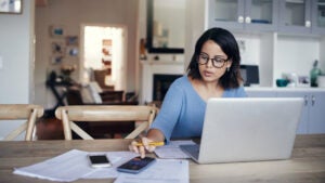 young woman using a laptop and calculator while working from home