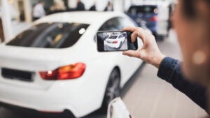 Person taking a picture of a car with their smartphone