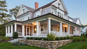 Exterior view of custom built home with exterior lighting and manicured landscaping.