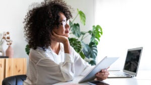 young woman working at home office using multiple devices