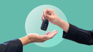 A close-up of two hands exchanging a car key fob. Image is on a green background.