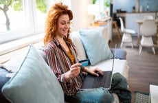 Young woman holding credit card and laptop