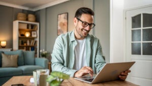 man looking at laptop, working online from his home