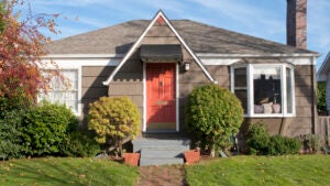 view of front lawn and brick pathway leading up to front door of home, autumn day, orange front door, blue sky