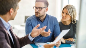 Young couple and their agent talking about plans on a meeting in the office.