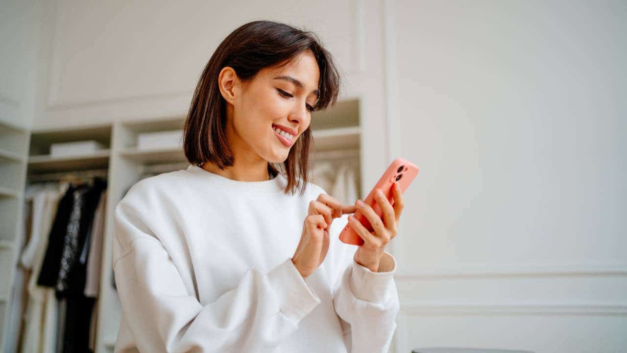 A businesswoman orders something on her phone while standing in a store.