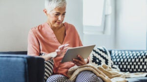 woman using digital tablet on sofa