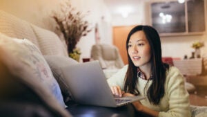 Woman working on laptop by the sofa in living room