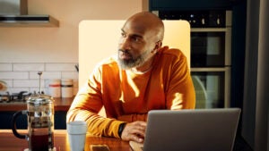 A man works on his laptop in his kitchen.